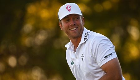 Gooch smiles whilst wearing a white top with LIV logos on it 