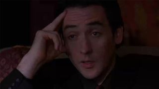 John Cusack with his fingers on his forehead looking stressed in Grosse Pointe Blanke