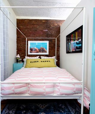 small bedroom in New York apartment with exposed brick wall and white four poster bed