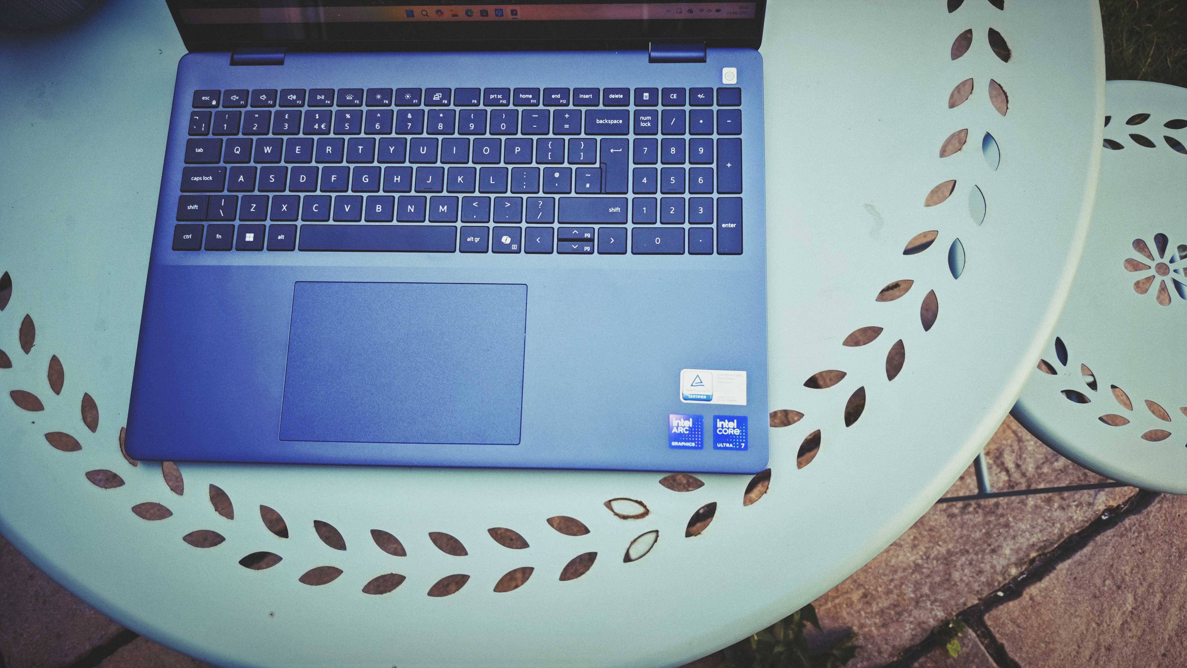 A Dell 16 Plus 2-in-1 laptop on a blue garden table