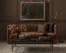 A living room with brown panelled walls, a brown sofa, and a coffee table with Halloween decor