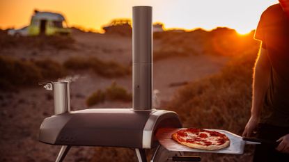 Ooni Fyra 12 pizza oven being used by an adult male to cook a pizza outside