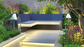 A beautiful small raised deck area with built in strip lights and up-lit plants in the background