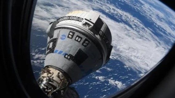 The Starliner capsule photographed through a porthole of the Internationl Space Station.