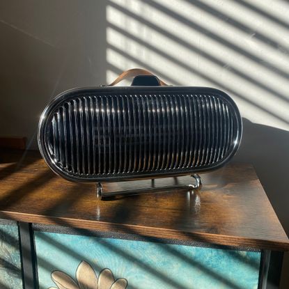 Swan 1.5kW Retro Ceramic Heater sitting on a sideboard with sunlight bouncing off the chrome grille