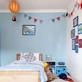 childrens bedroom with wallpaper on wall and bunting flag