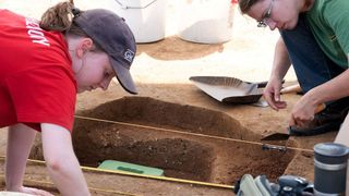 Two people excavate a burial site in Maryland. 