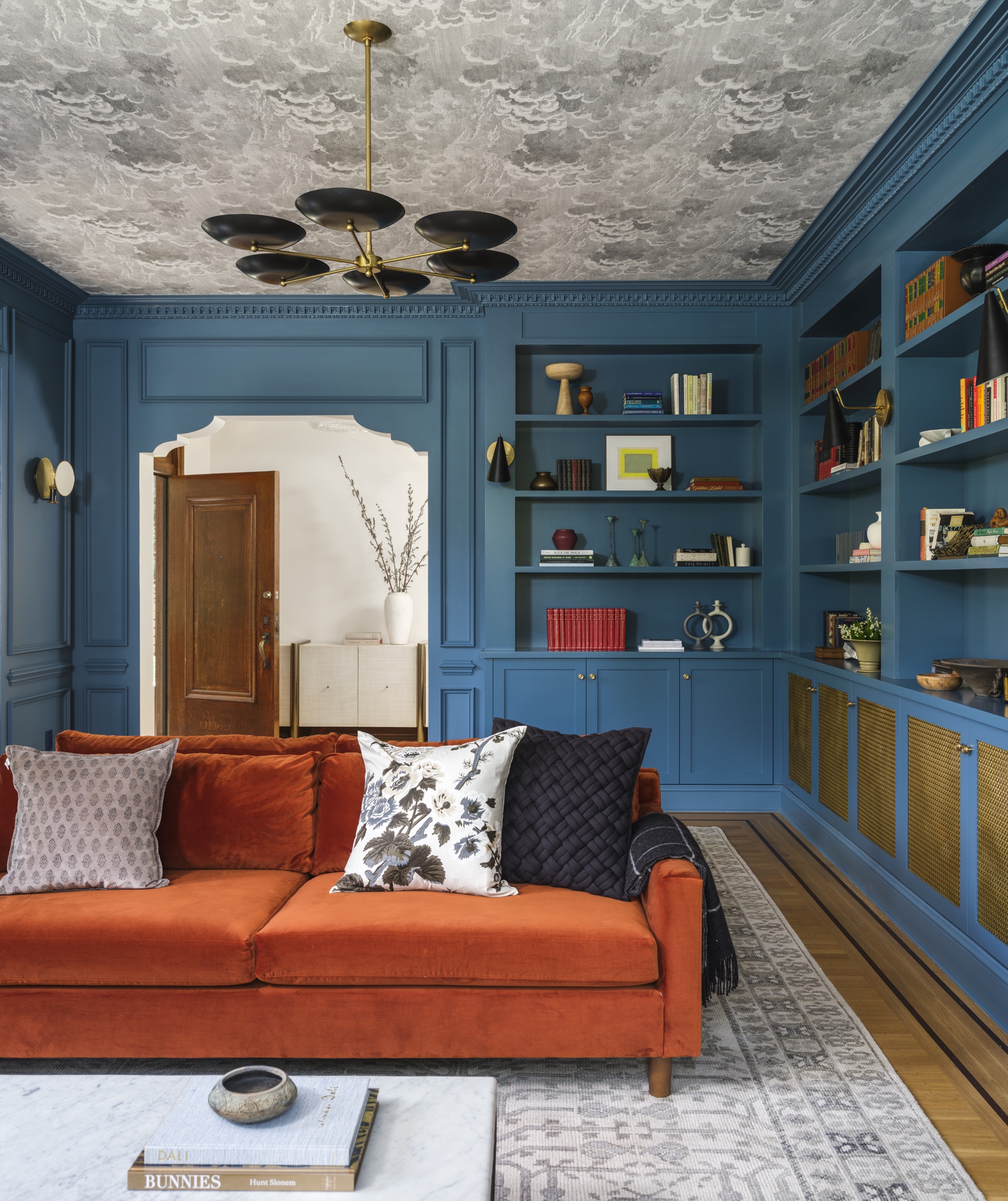 Blue living room with custom millwork, wallpapered ceiling, and rust sofa by Banner Day Interiors