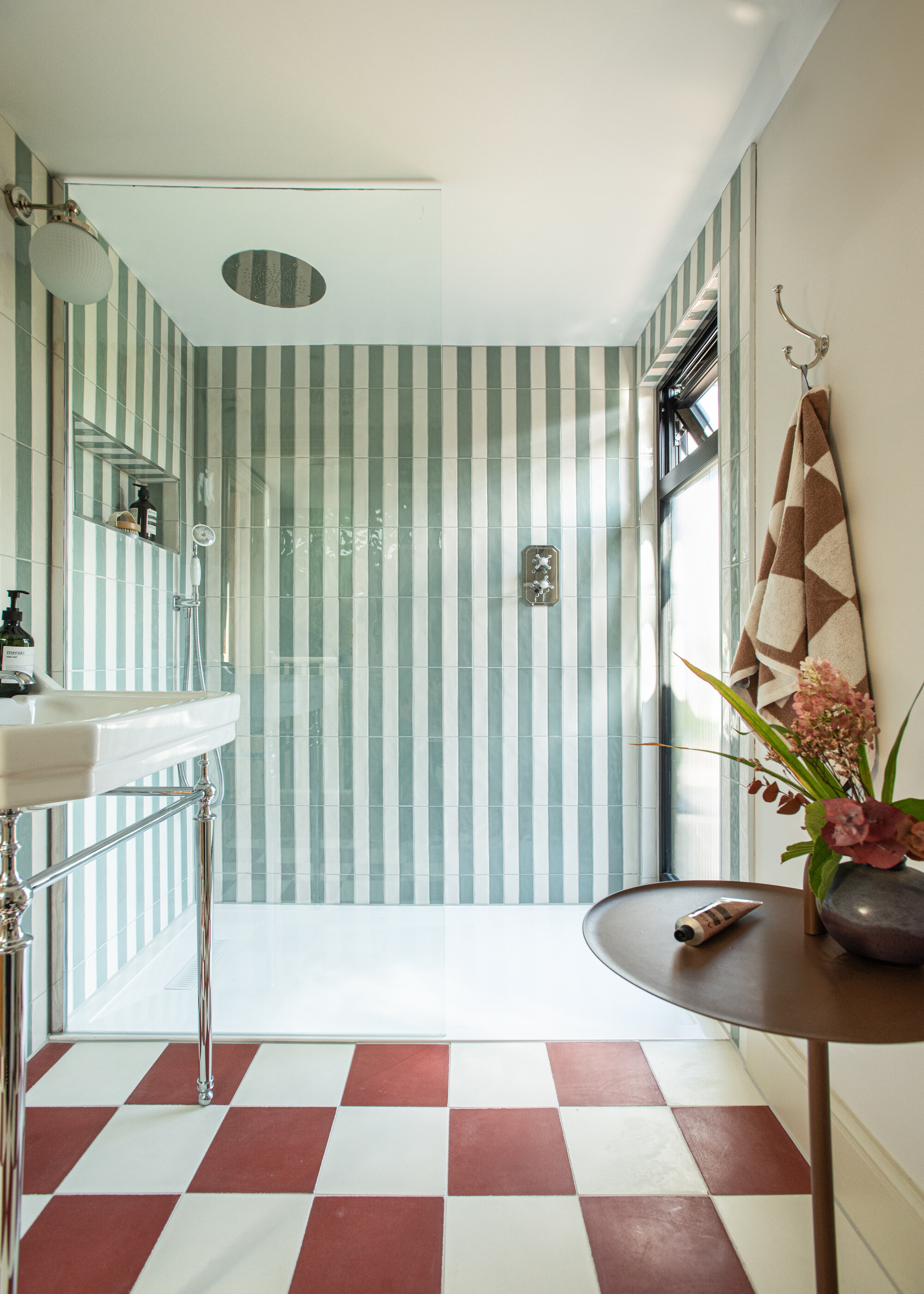 A bathroom with a large walk-in shower with blue and white striped tiles
