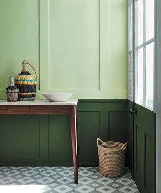 colors that go with dark green, two tone green entryway with dark green painted to dado rail, light green above, console table, pale green graphic tiles, basket