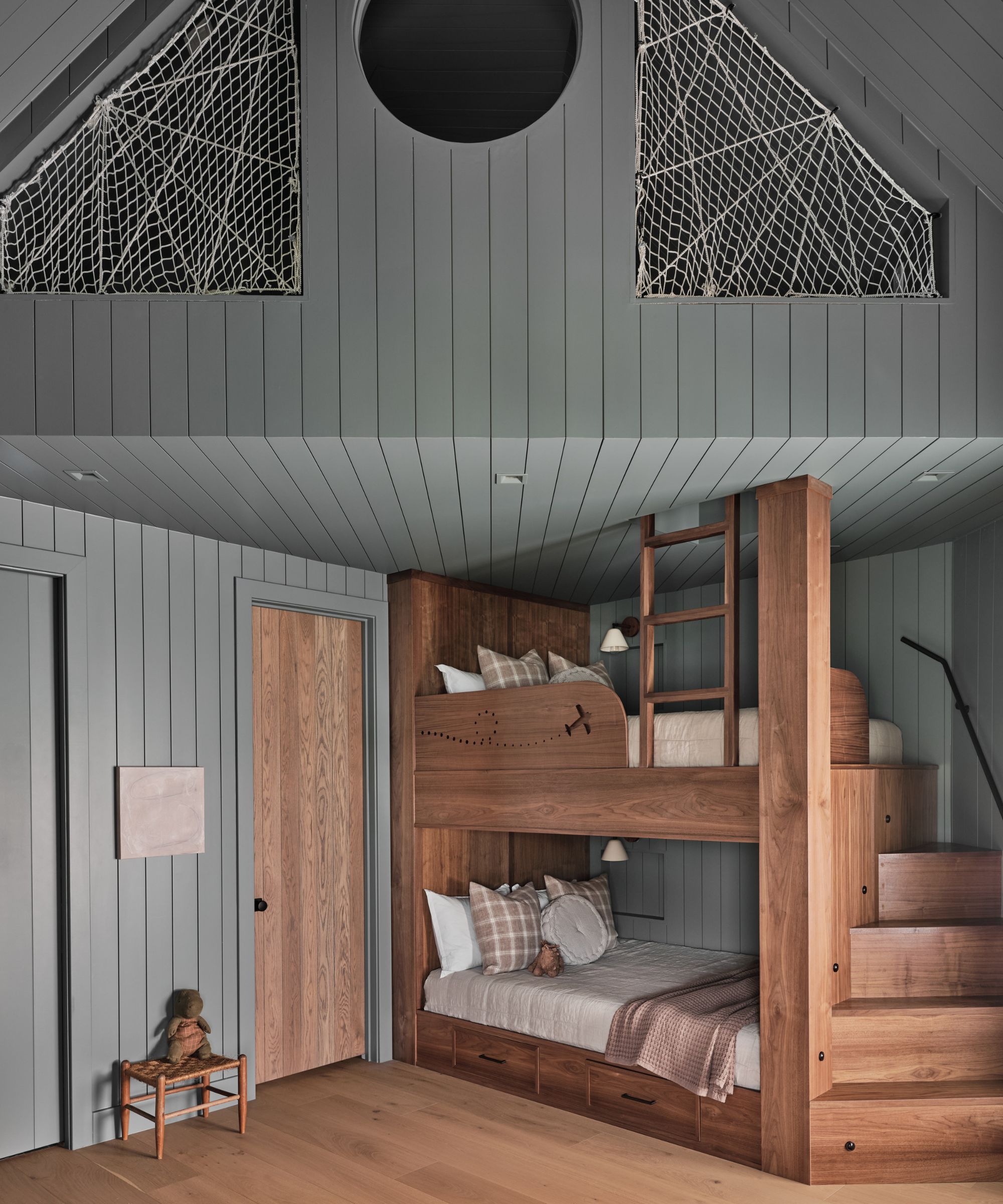A children&#039;s bedroom with wall paneling painted mid-blue and wooden accents