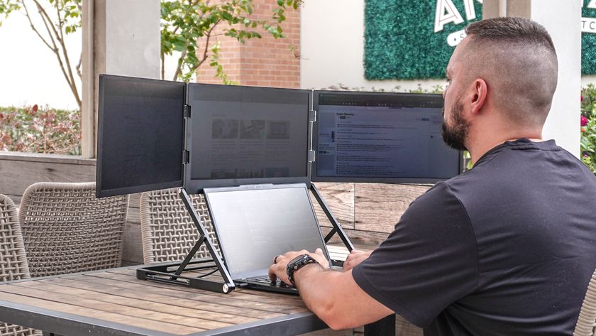 A person working on the Aura Triple Aero 15.6 Pro Max portable monitor with a laptop on a table outside at a coffee shop