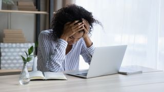 woman with head in hands in front of laptop
