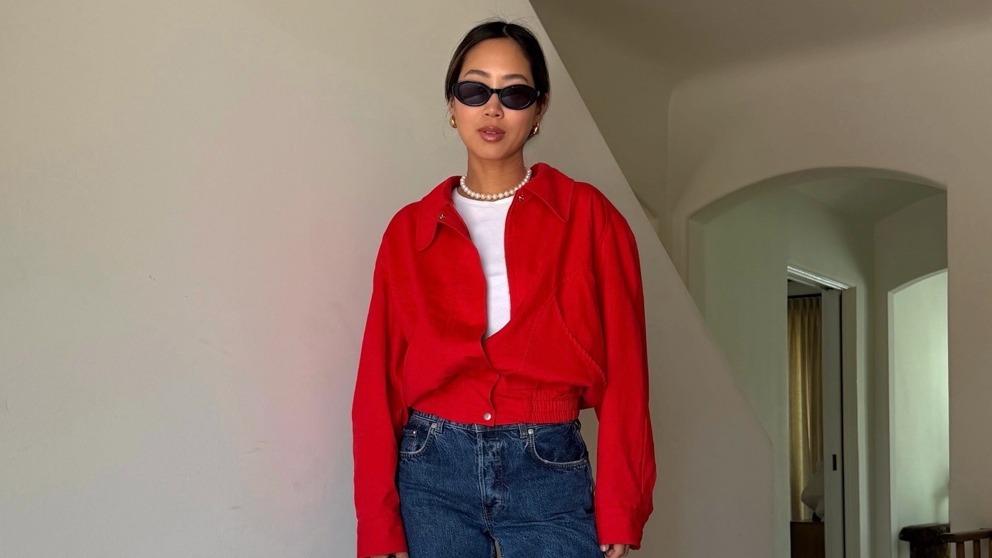 Aimee Song wears a red jacket, dark wash blue jeans, Chanel flats and purse, and a pearl necklace.