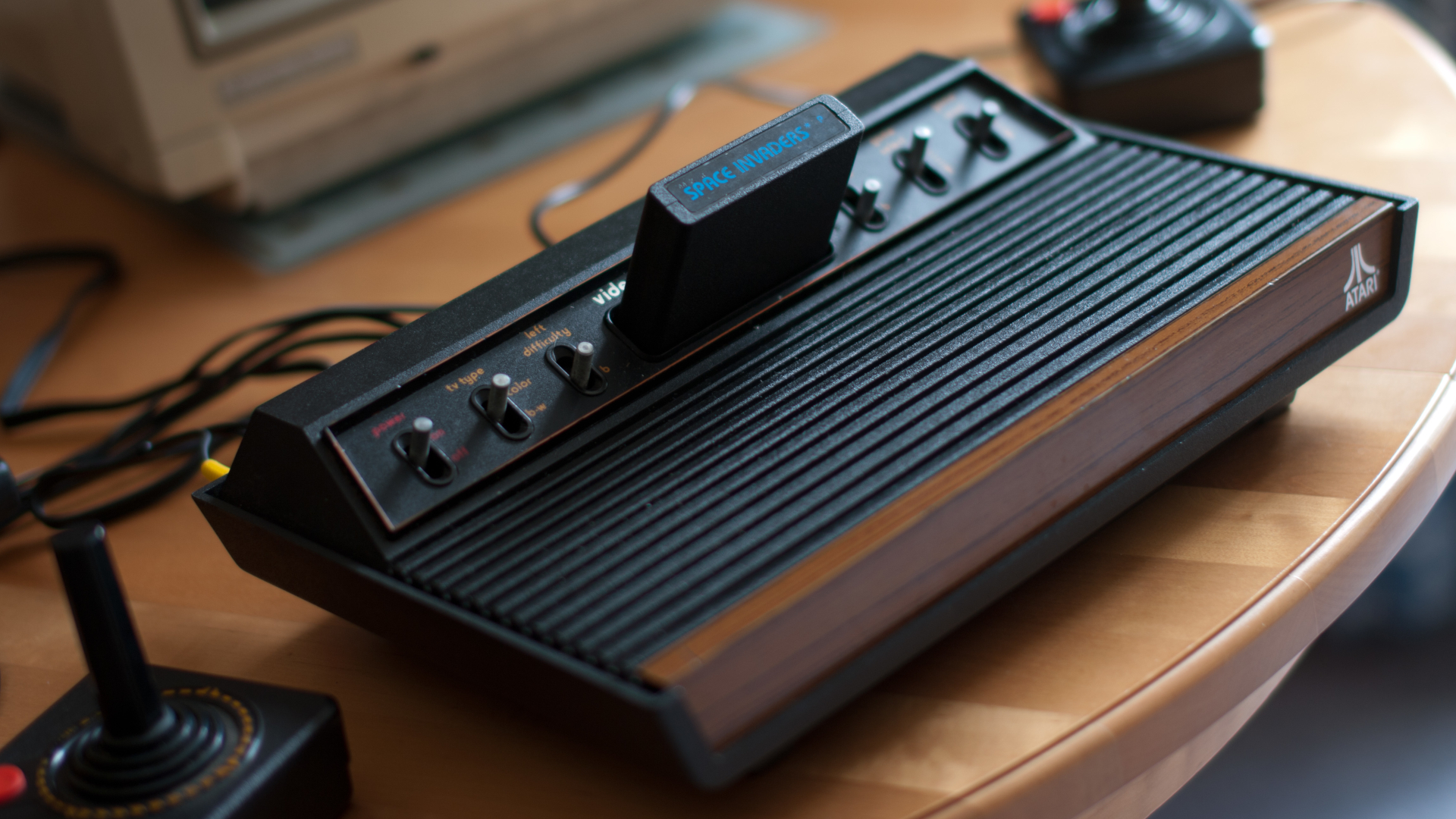 Atari 2600 VCS console, full view, with joysticks and Commodore 1084S monitor partially visible. 1978 six switch model. Space Invaders game is inserted.
