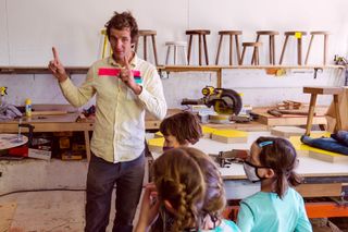 Artist Larry Bamburg with a group of girls in the wooden workshop in Marfa