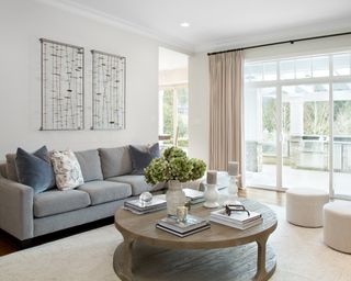 A white living room with grey sofa, white rug and wooden coffee table
