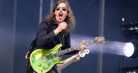 Mikael &Aring;kerfeldt pulls a face while playing his green PRS Custom 24 live onstage at Tons of Rock 2024 with Opeth. He wears gold aviators and a black shirt. 
