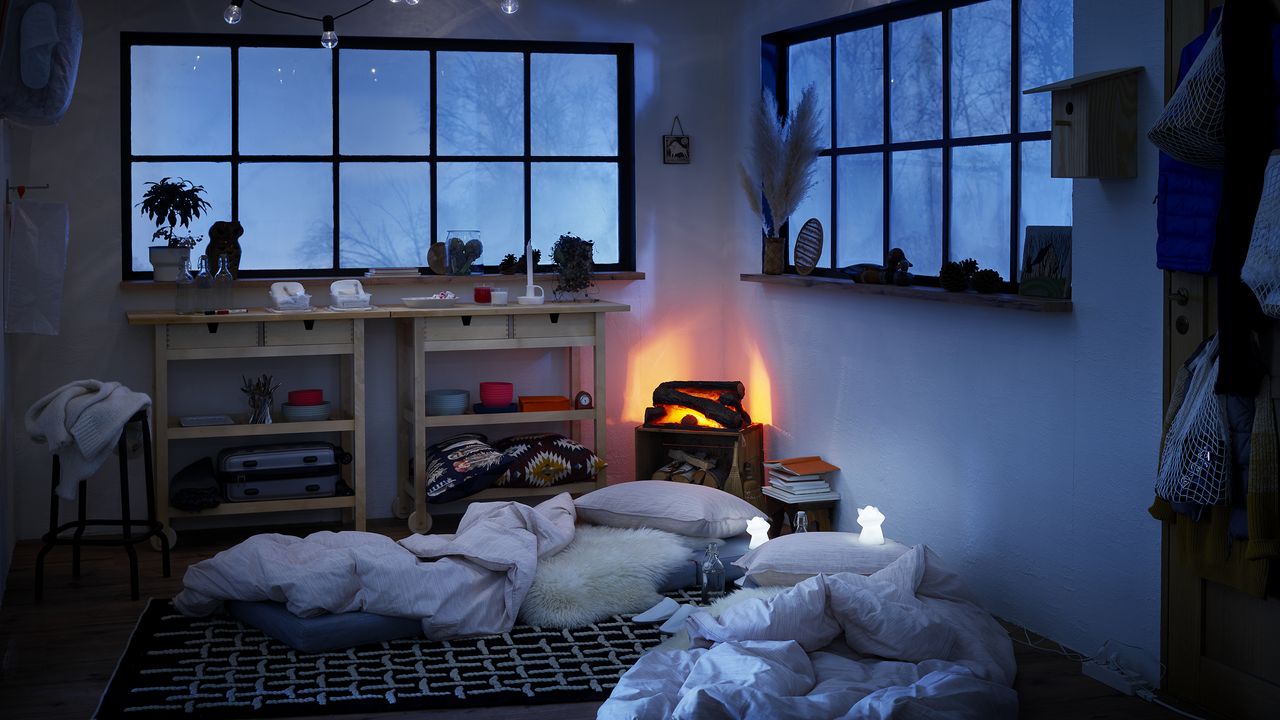 A folded mattress on floor in bedroom at night with festoon lighting decor 