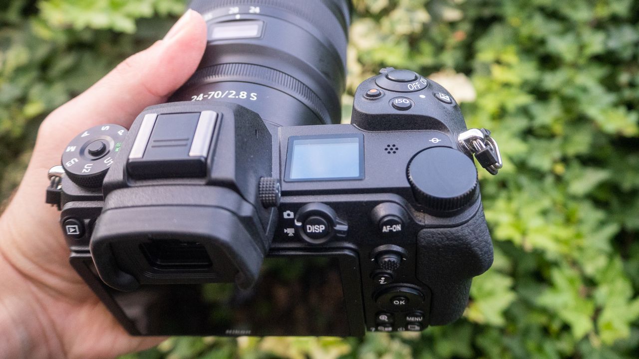 A photo of the Nikon Z6 II held in a hand with leaves in the background.