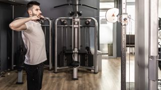 Man performs the face pull exercise using a cable machine