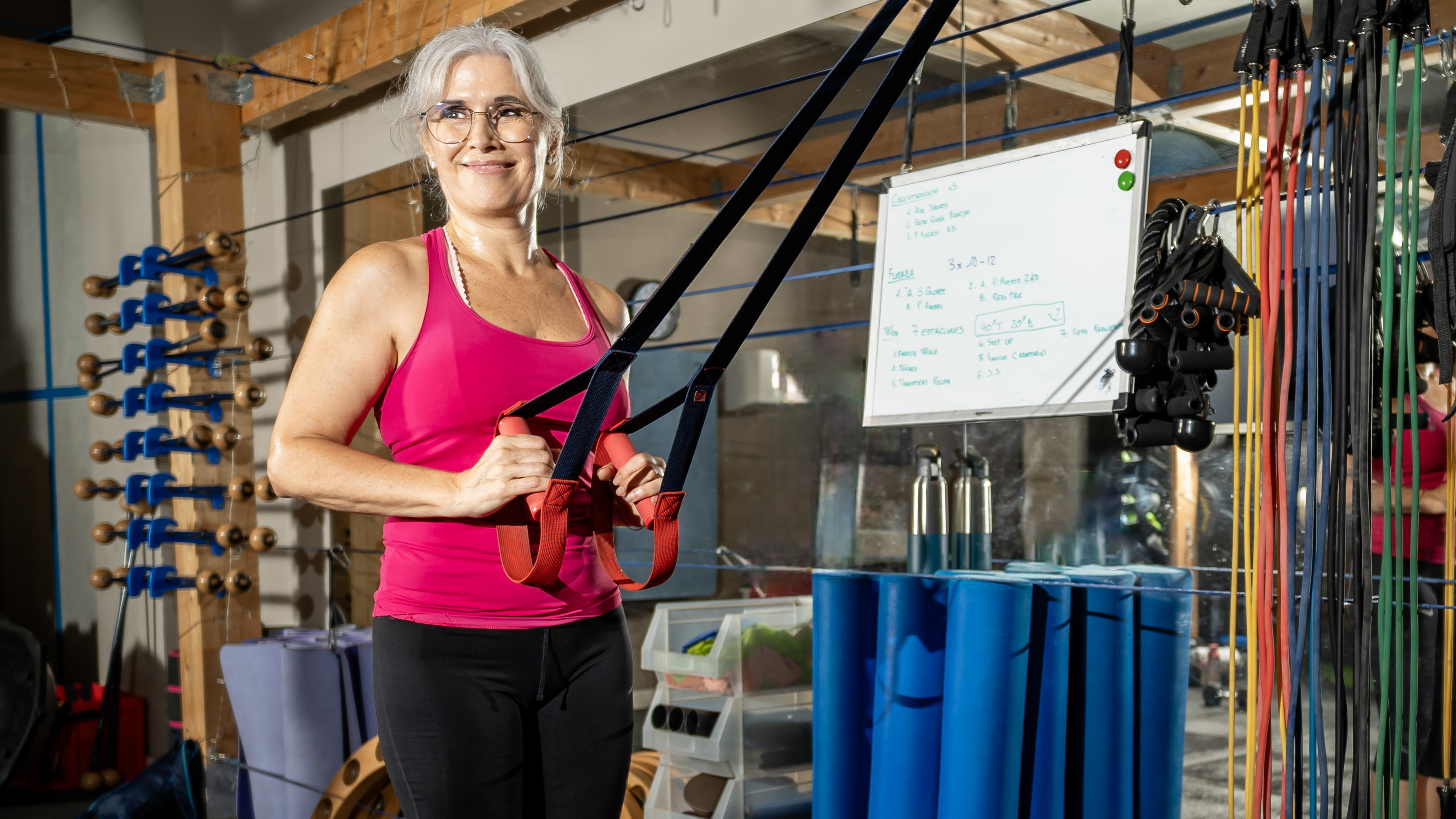 Woman holding handles of suspension trainer in gym