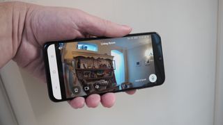 Phone held in a hand showing the app for a Eufy Indoor Cam C120