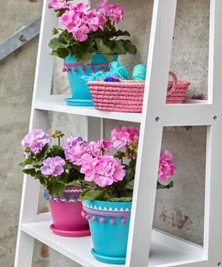 Bright blue and pink painted pots with a pompom trim