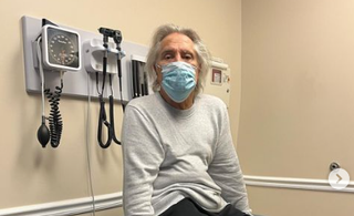 A picture of Geezer Butler at a medical facility wearing a medical mask