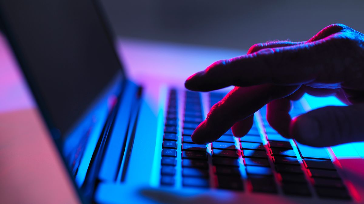 A man types on a laptop in the dark