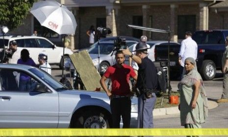 A man speaks with a police officer with a CNN television crew in the background outside the Sikh Temple of Wisconsin, in Oak Creek, on Aug. 6: News coverage of the Sikh temple shooting as dro