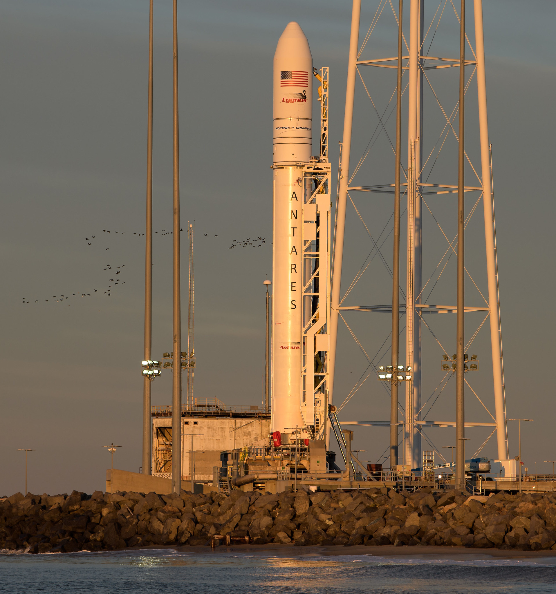 a rocket beside launch towers and behind water