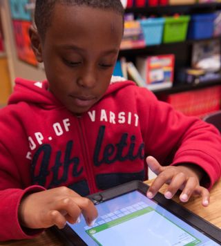 Boy uses touch screen tablet computer.