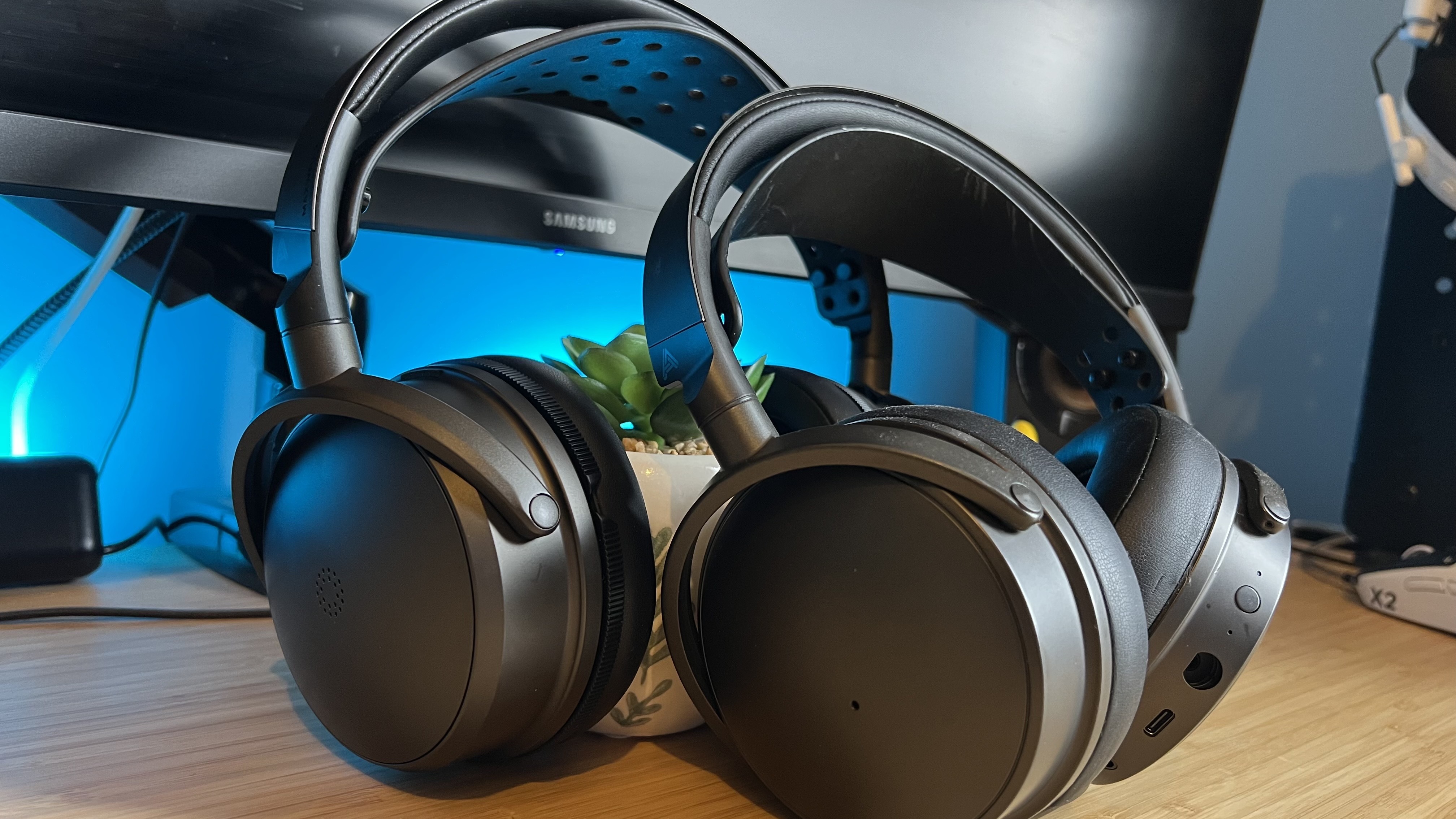 Audeze Maxwell headset leaning on an Audeze Maxwell 2 headset on a wooden desk