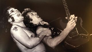 Ozzy Osbourne grabs Brad Gillis in excitement as Gillis rips a solo on his red Fernandes S-style