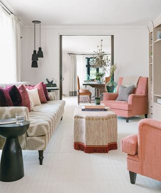 Open plan living room with white walls, pink chairs and pocket doors