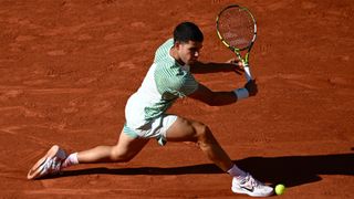 Carlos Alcaraz stretches for a backhand on clay at the French Open