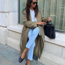 Woman wearing jeans, trench-coat and black ballet flats