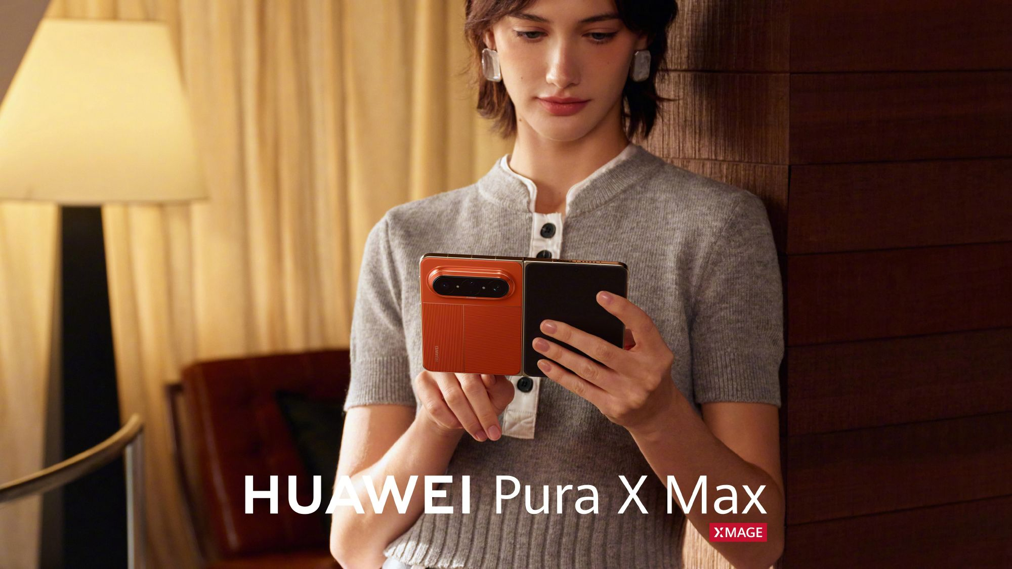 A woman looking at an orange Huawei Pura X Max in hand