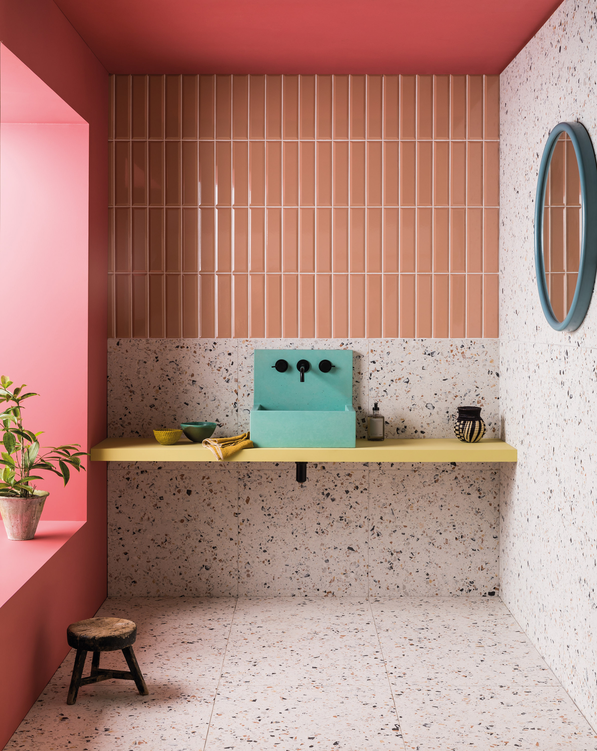 Terrazzo tiles in pink in a colorful bathroom with a blue basin and pink metro tiles