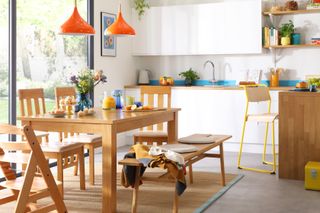 white open plan kitchen with orange pendant lights above dining table
