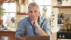 An older businessman is sitting at his kitchen table.