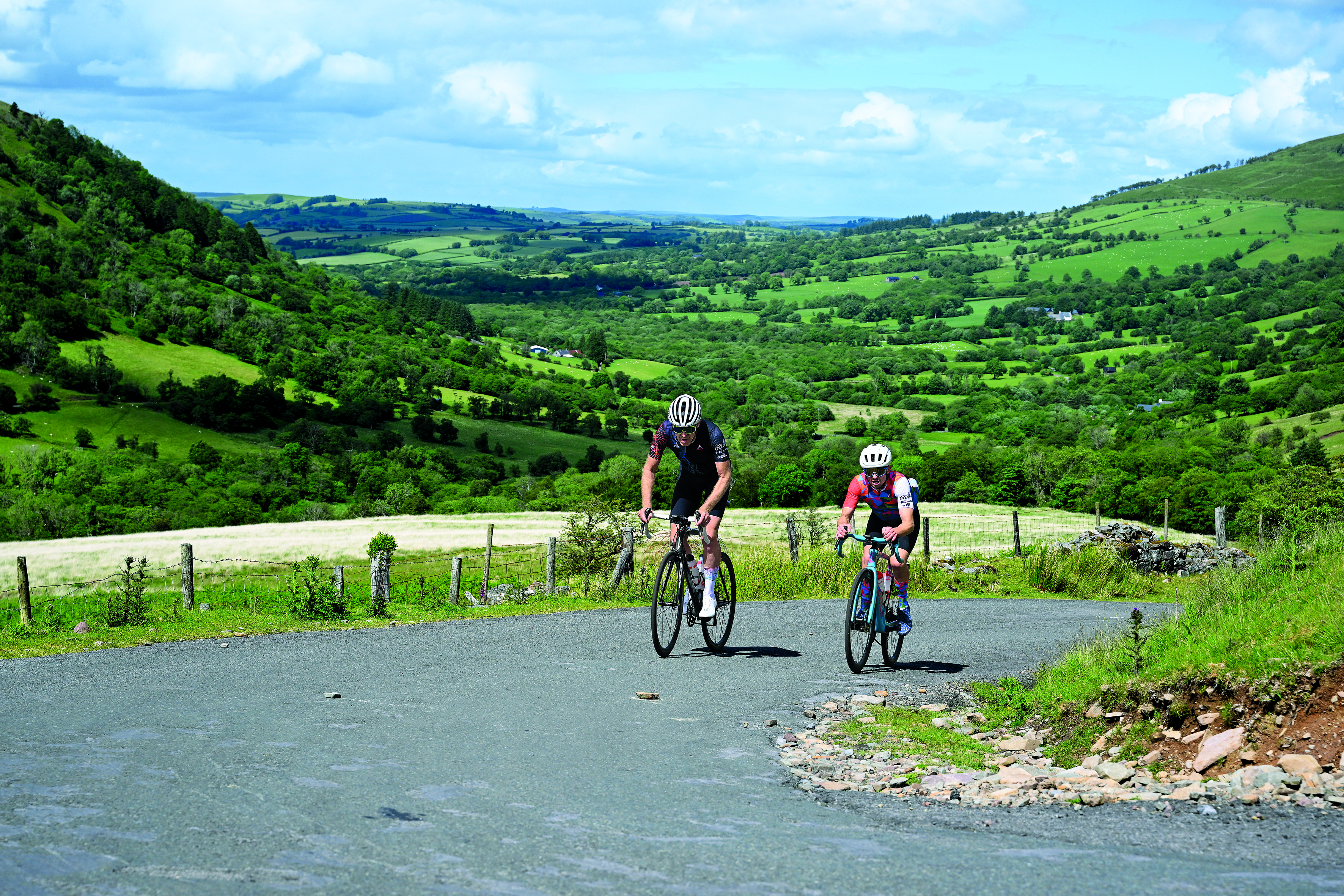 Two riders side by side climb a hairpin