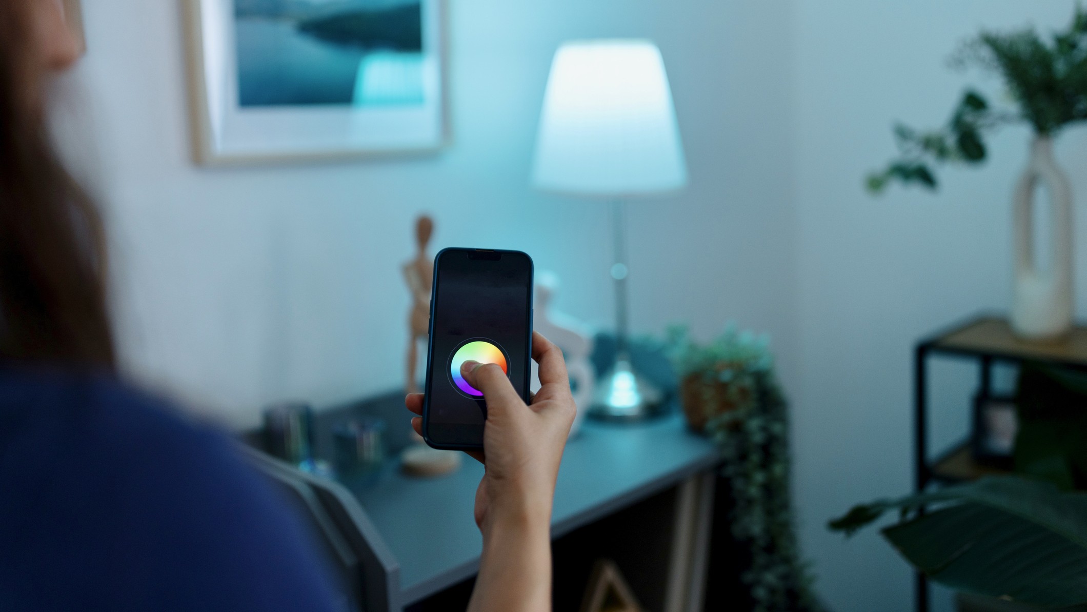 Person using mobile app to control smart light bulb in lamp