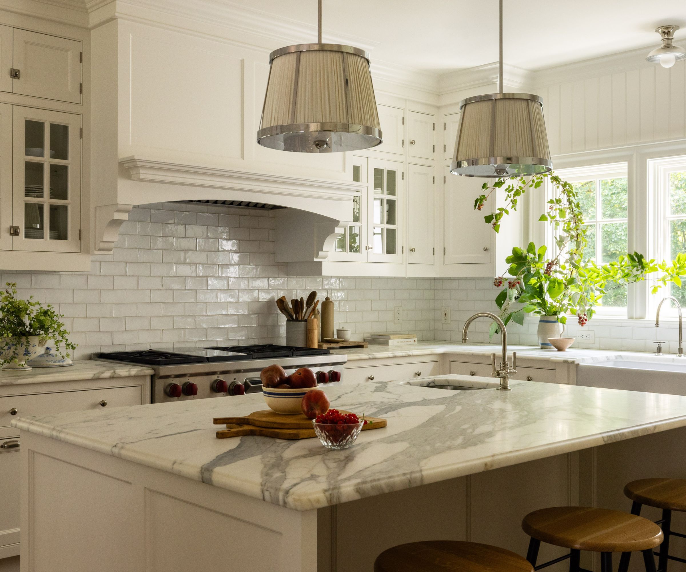 Farmhouse kitchen with subway tiles, marble island, pendant lights and white cabinets