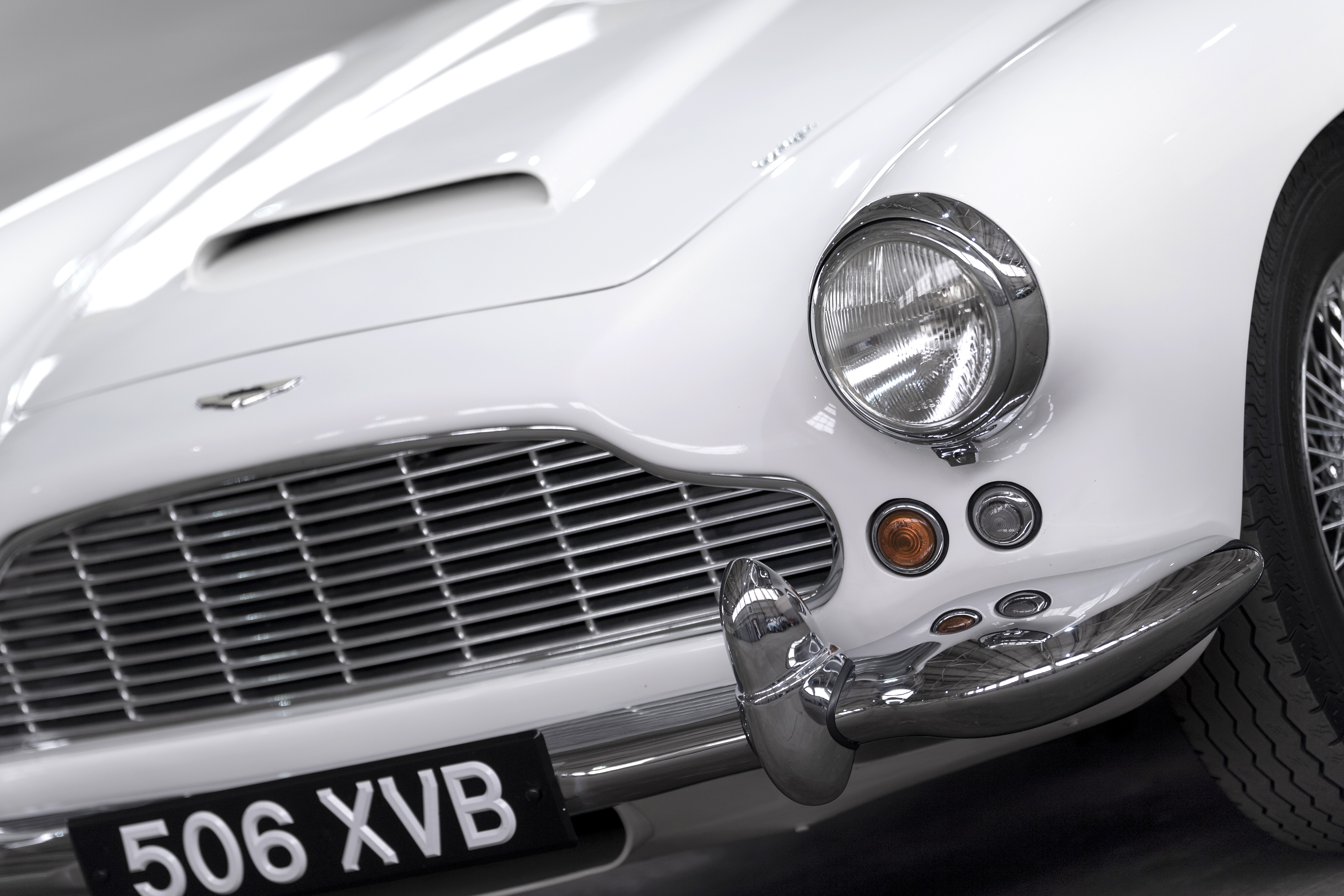 Details of the Aston Martin DB4, painted white, in a grey airplane hangar