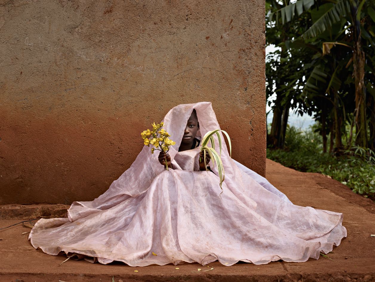 Child in pink dress holding flowers sat on the floor