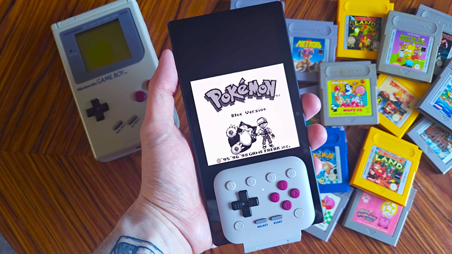 Hand holding Razer Edge with 8Bitdo FlipPad connected with Pokemon Blue start screen displayed.