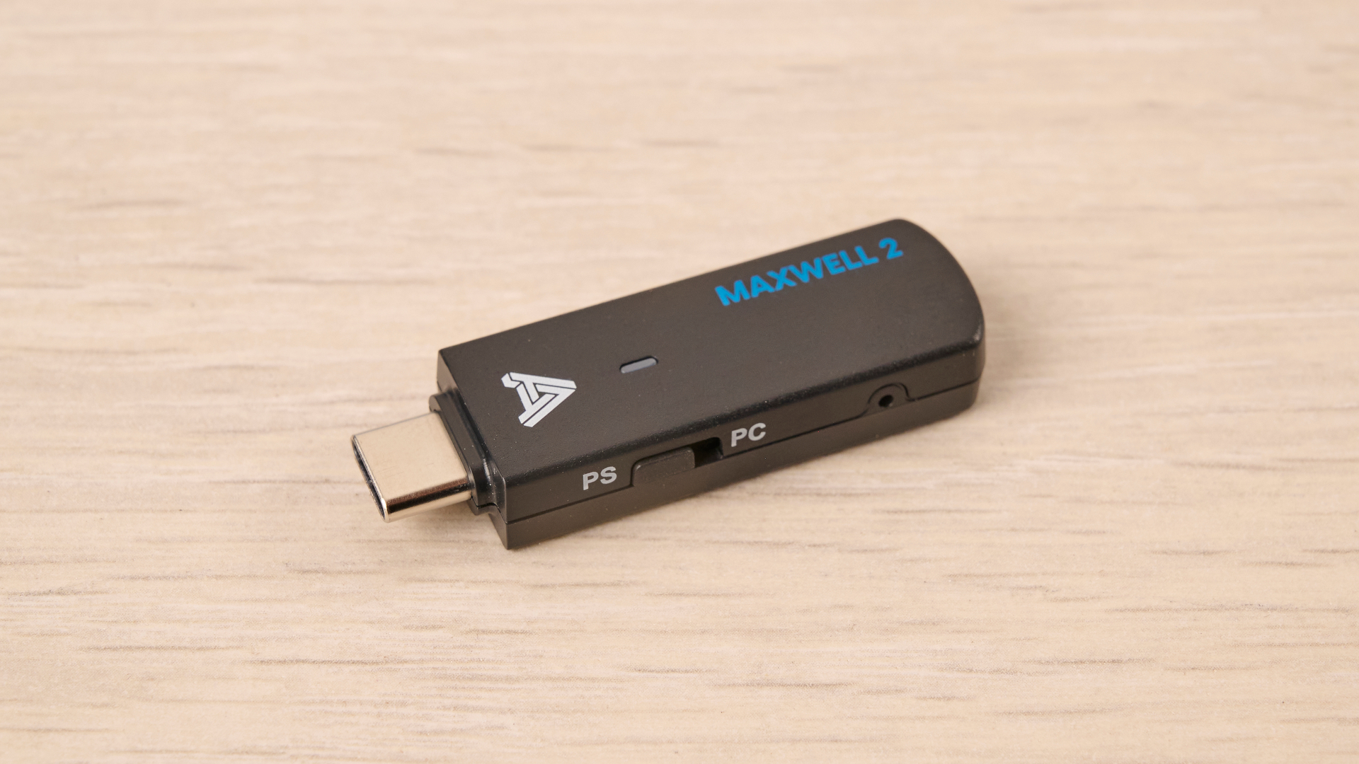 The Audeze Maxwell 2 ANC USB-C dongle, placed on a wooden desk