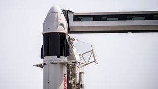 A white and black SpaceX Crew Dragon spacecraft atop its Falcon 9 rocket on the launch pad for a March 2, 2024 launch.